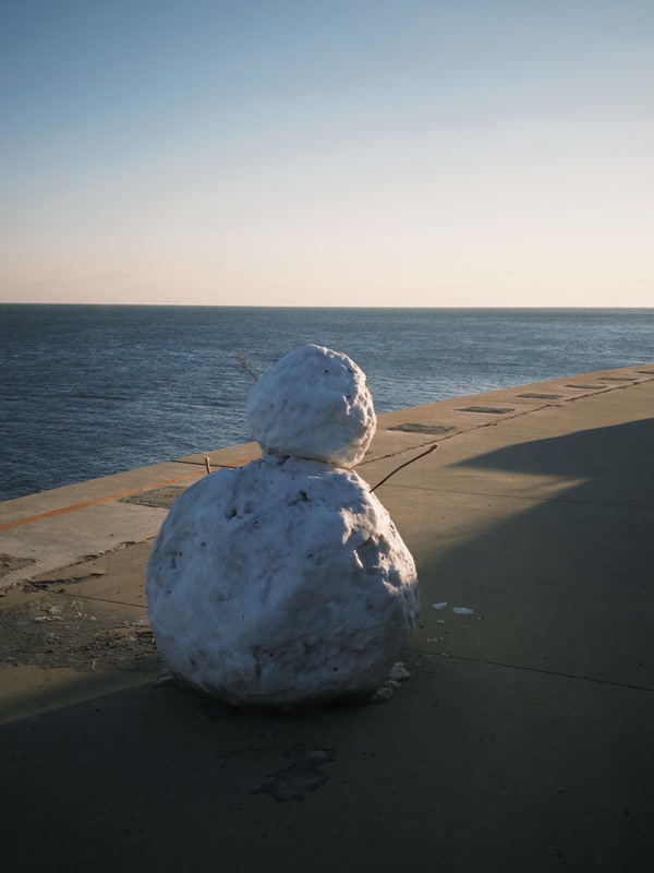 A snowman facing the winter sea