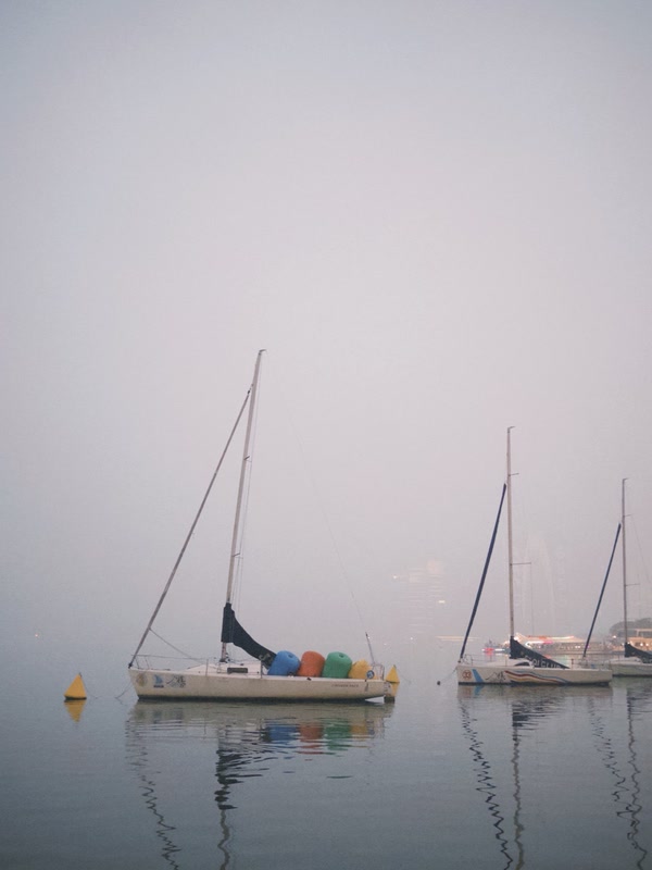 Sailboats drifting through pale mist